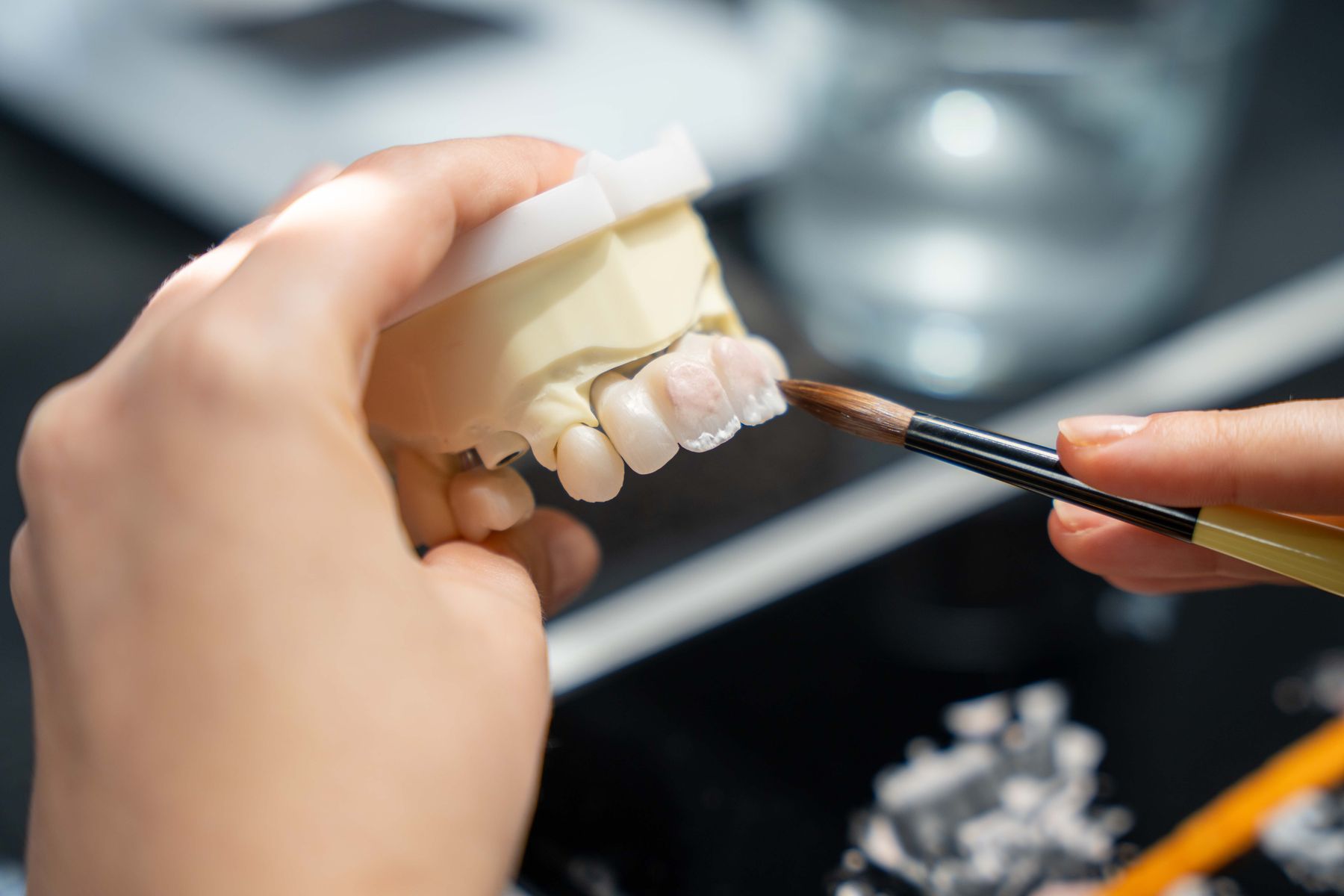 Zahntechnikerin individualisiert eine vollkeramische Arbeit mit dem Pinsel im Dentallabor Norderstedt